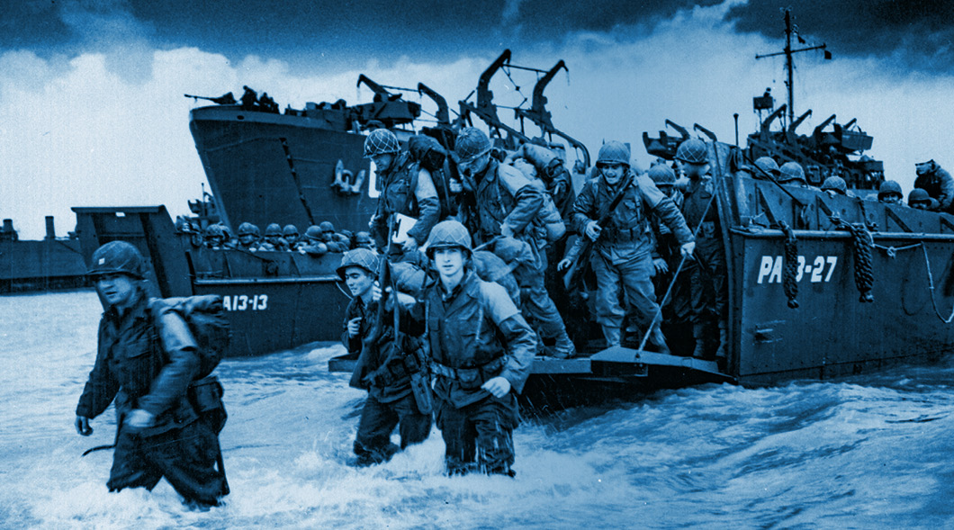 Black & white photo of U.S. Troops landing on the beach in France in 1944