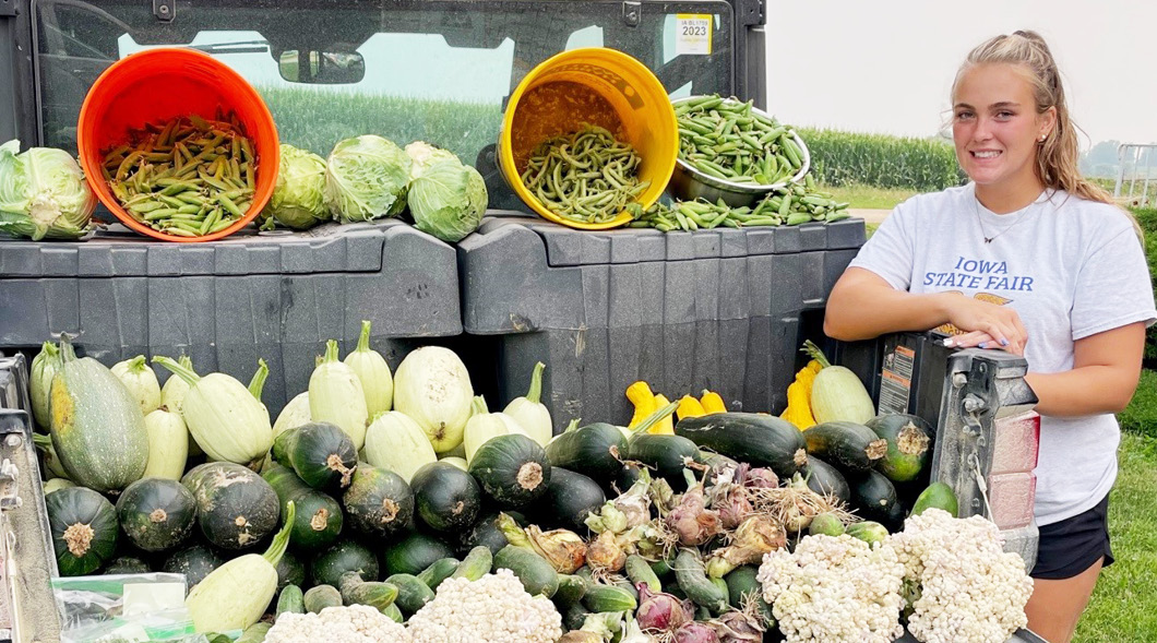 Photo of a teen posing next to a large variety of fresh produce