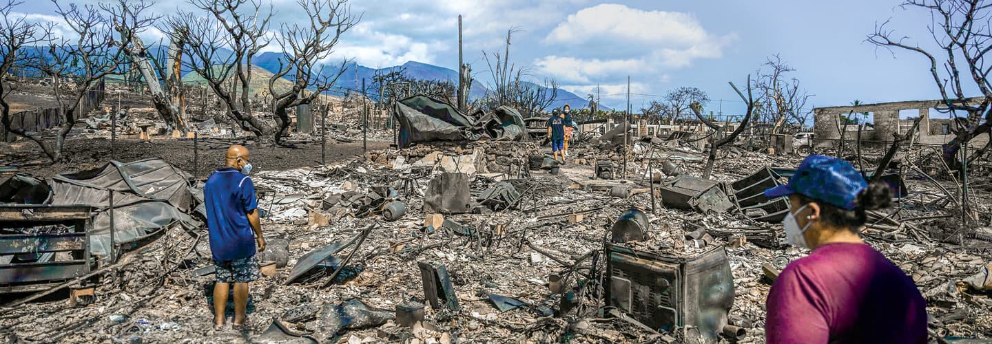 Image of two people standing in front of the aftermath of destruction