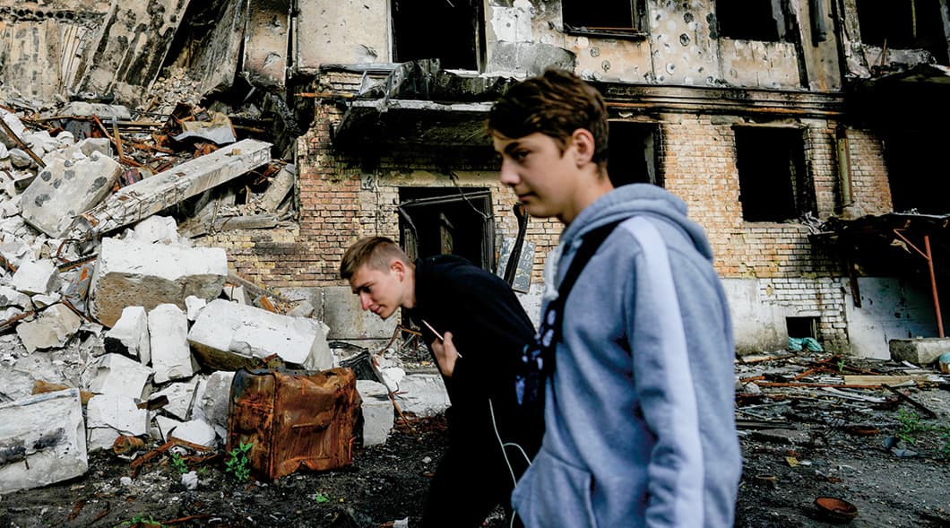 Photo of two people walking by destroyed buildings