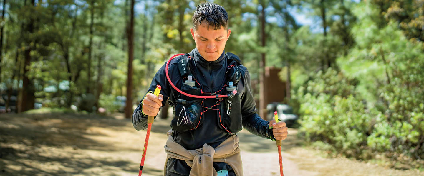 Image of a person walking in woods with walking sticks